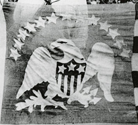 A bald eagle clutching arrows is under an arc of 13 stars