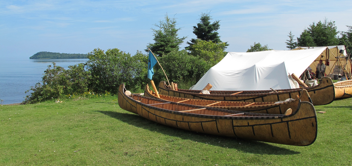 Two birch bark canoes pulled ashore above a large lake