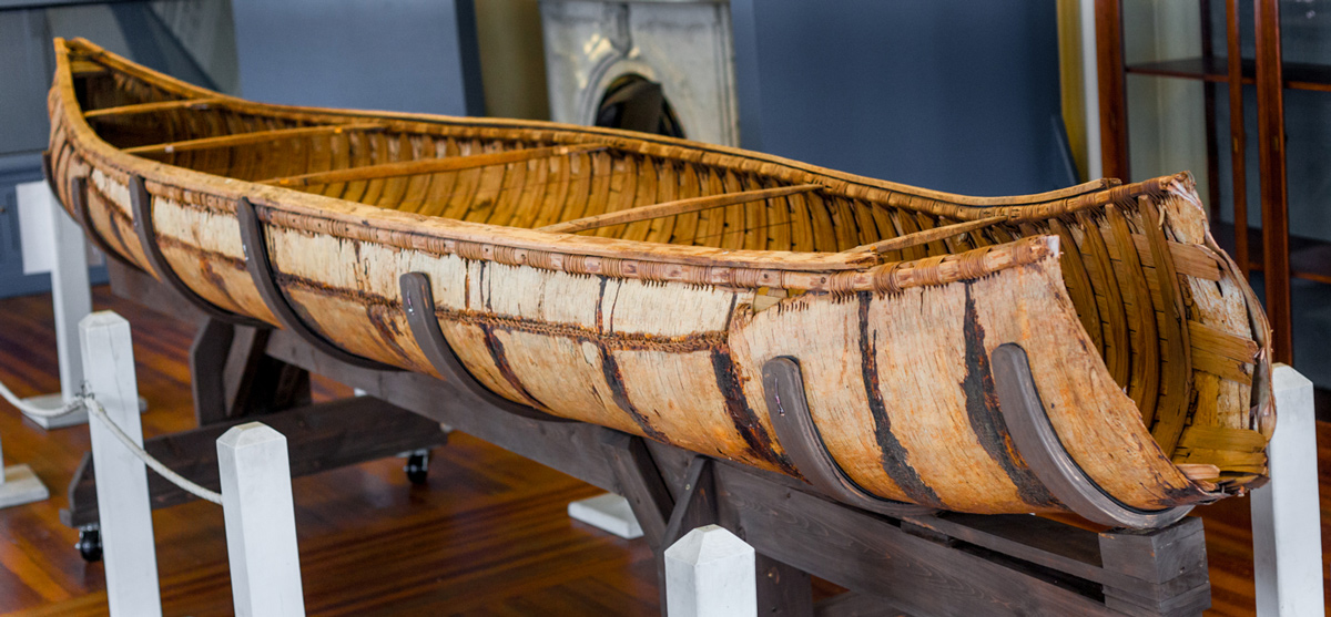 An old birch bark canoe with the front cut away.