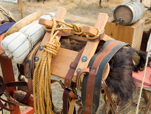 A saddle with boards, leather belts, and buffalo hair blanket
