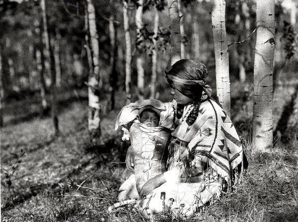 A young Indian mother holds her child in a papoose