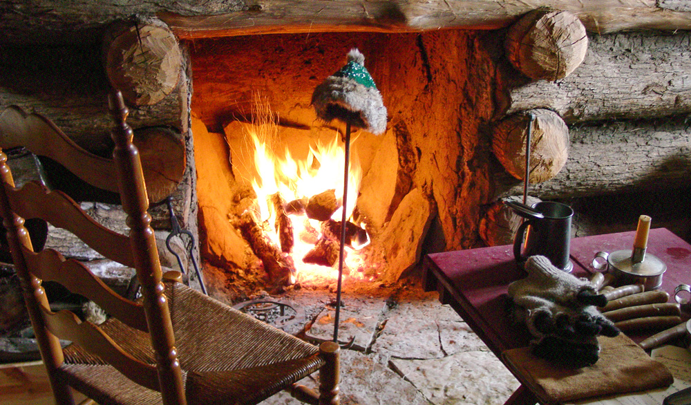 A wool hat dries by a lonely cabin fire