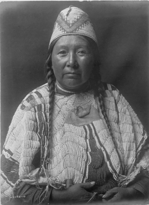 Indian with woven had and skirt covered with dentalium shells