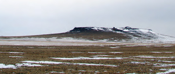 Small hill with a flat top with patchy snow