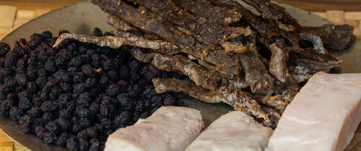 metal plate with 3 piles: dark, dried berries, strips of white fat, and strips of dark, shriveled meat