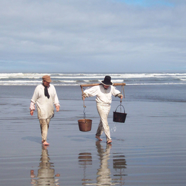 Two soldiers in fatigues haul saltwater at the beach